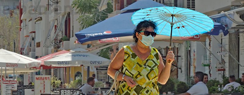 Frau mit Sonnenschirm und Maske